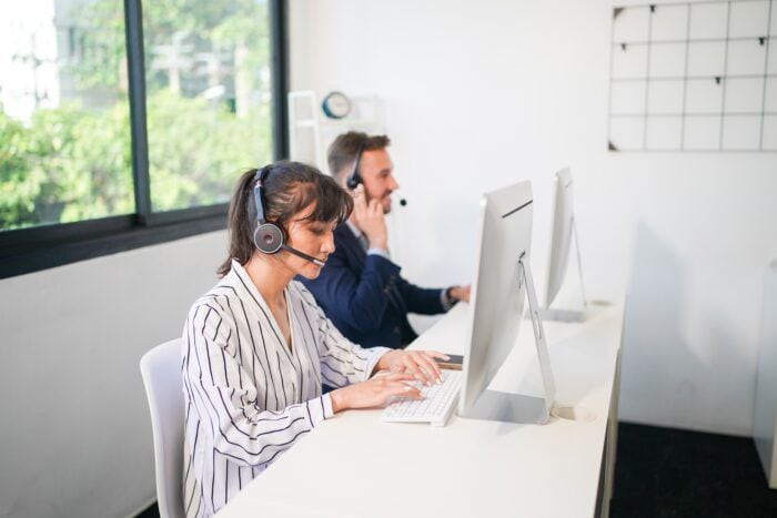 phone answering service business - Charming business lady in headphones talking with business partner on laptop