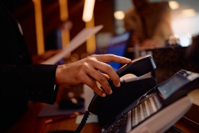 respite care phone answering service - Close up of receptionist answering a phone call while working in a hotel.