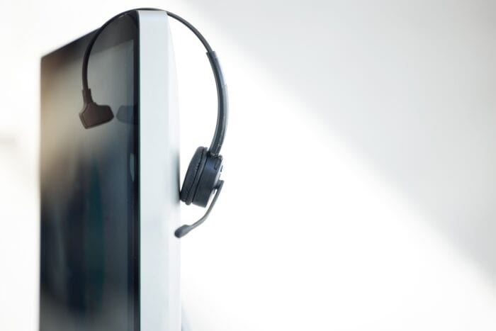 ai call centers - Computer, headphones and call center telemarketing background in office for contact us, virtual onl