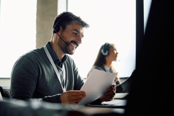 ai call center agent - Happy call center agent with headset using laptop in the office.