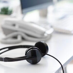 Helpline operator's workplace with modern headphones at call centre, empty space