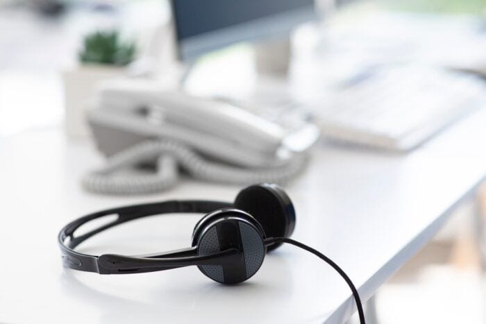 Helpline operator's workplace with modern headphones at call centre, empty space