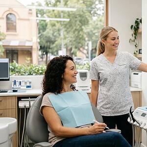 A dental professional explains digital dental health data on a large screen to a patient in a modern dental clinic, showcasing AI-powered dental consultation tools.