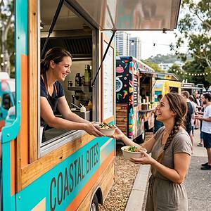 An image of a food truck named Coastal Eats serving customers at an outdoor festival, with people enjoying food and lively atmosphere in the background.
