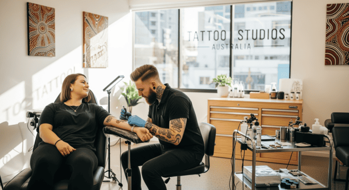 A tattoo artist in a modern studio in Australia is creating a tattoo for a client, showcasing professional tattooing services in a bright, stylish environment.